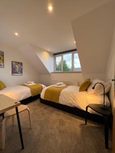 a bedroom with two beds and a table at Ty Gwyn Holiday Cottage - Llanbedr Dyffryn Clwyd - Ruthin in llanbedr-dyffryn-clwyd