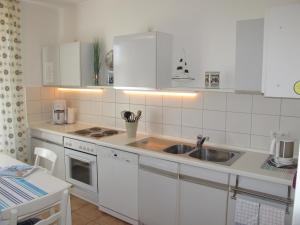 a kitchen with white cabinets and a sink at FeWo ABDENA DORN200 in Dornum