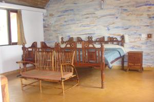 1 dormitorio con cama y pared de piedra en O'Land Plantation en Kolakambe