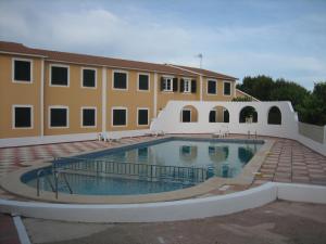a building with a swimming pool in front of a building at Precioso apartamento de dos hab. en Calan Bosch in Ciutadella