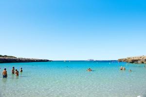 un gruppo di persone in acqua su una spiaggia di Precioso apartamento de dos hab. en Calan Bosch a Ciutadella