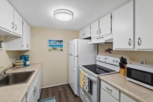 a kitchen with white cabinets and a white refrigerator at Sea Escape - Condo with Pool Hot Tub Plus Private Community Beach in St. Petersburg