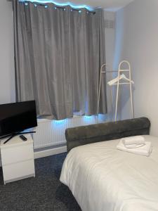 - une chambre avec un lit, une télévision et une fenêtre dans l'établissement Modern 4 Bedroom House 10 mins from East Croydon with Garden and Free parking, à South Norwood