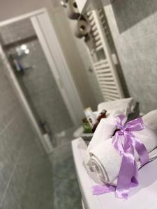 una pila de toallas con un moño púrpura en la encimera del baño en L' anfora Locazione Turistica, en Terni