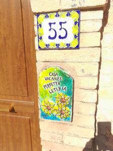 een bord op een muur naast een deur bij Casa vacanze Perfecta Laetitia Assisi in Tordandrea