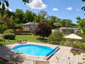 una piscina en un patio con sombrilla en Meavy Cottage en Totnes