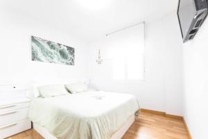 a white bedroom with a bed and a window at Apartamento cerra playa in Gijón