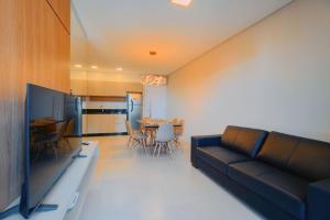 a living room with a couch and a table with chairs at Apartamento Novinho, pertinho da Praia de Bombinhas in Bombinhas
