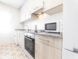 a kitchen with white cabinets and a microwave at Apartamento cerra playa in Gijón