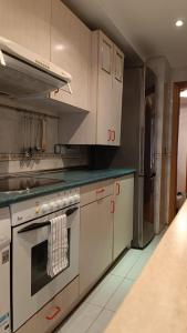 uma cozinha com armários brancos e um forno com placa de fogão em Apartamento Calle Turco 13 em Zaragoza