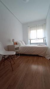 um quarto branco com uma cama grande e uma cadeira em Apartamento Calle Turco 13 em Zaragoza