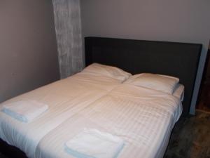 Una cama con sábanas blancas y dos toallas. en Urban City Centre Hostel, en Bruselas