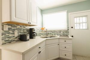 uma cozinha com armários brancos, um lavatório e uma janela em Inviting Home in Historic Leimert Park em Los Angeles