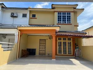 ein Haus mit einer orangefarbenen Eingangstür und einer Terrasse in der Unterkunft D’Lestari Homestay in Seri Kembangan