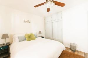 een slaapkamer met een wit bed en een plafondventilator bij Spring Charmer In The Heart Of The City in Los Angeles