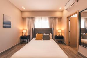 een slaapkamer met een groot bed met 2 nachtkastjes bij Fully Serviced Apartment at Regatta Living - 2G in Santo Domingo