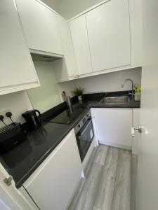 a kitchen with white cabinets and a sink at Spacious 2 Bedroom flat in Paddington in London
