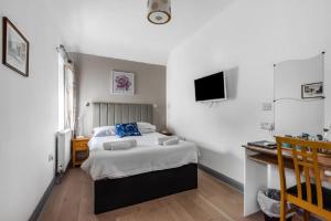 a bedroom with a bed and a desk and a television at Oxford Guest House in Oxford