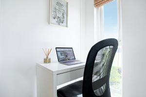 a laptop computer sitting on a white desk with a chair at Duplex 2 Bedroom Apartment - Close to City Centre - Balcony, Free Parking, Fast Wifi & Smart TVs by Yoko Property in Milton Keynes