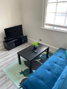a living room with a blue couch and a coffee table at Spacious 2 Bedroom flat in Paddington in London
