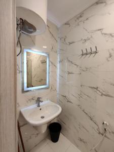 ein weißes Badezimmer mit einem Waschbecken und einem Spiegel in der Unterkunft (42)m luxury room in Ash Shumaysānī