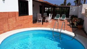a swimming pool with chairs and a table on a patio at La Quinta Villas in San Miguel de Abona