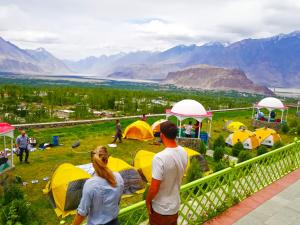 a group of people standing in a field with tents at Hotel Mountain Lodge Skardu in Skardu