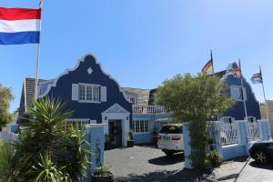 a blue house with flags in front of it at Birkenhead Manor in Bloubergstrand