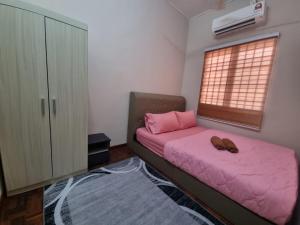 1 dormitorio con cama rosa y ventana en D’Lestari Homestay en Seri Kembangan