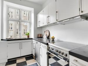 a kitchen with white cabinets and black counter tops at Sanders Stage - Perfectly Planned Three-Bedroom Apartment Near Nyhavn in Copenhagen