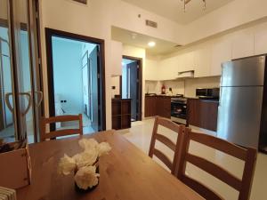 a kitchen with a wooden table and a stainless steel refrigerator at 5*Amenities-2Br-15 min DxbApt,20min to Dubai Mall in Dubai