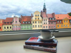 a cup of coffee sitting on a stack of books next to a window at Rynek 45 Apartament in Wrocław