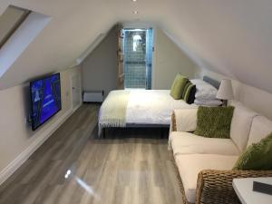 a bedroom with a bed and a couch and a tv at Oaks Barn in Chinnor