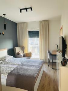 1 dormitorio con 1 cama, 1 silla y TV en Tila II, en Wałcz