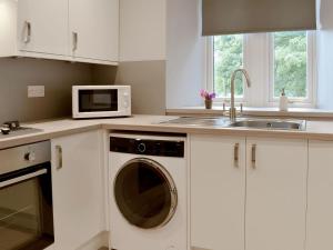 una cucina con lavatrice e lavandino di The Lodge a Linlithgow
