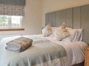 Una cama blanca con almohadas y una manta. en The Lodge en Linlithgow