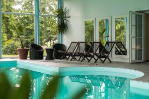 een kamer met stoelen en een zwembad bij Ziemupes Muiža & SPA in Ziemupe