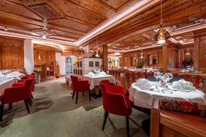 un restaurante con mesas blancas y sillas rojas en Hotel Bergkristall en Silbertal