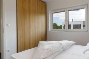 a bedroom with a white bed with a window at LUXUS Appartement am Golfplatz und Therme Lutzmannsburg in Zsira