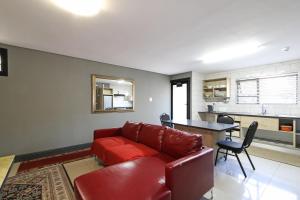 - un salon avec un canapé rouge et une table dans l'établissement Camdene Guesthouse, au Cap