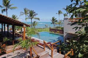 a resort swimming pool with the ocean in the background at Santa Aldeia Hotel in Arraial d'Ajuda