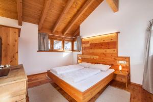 1 dormitorio con 1 cama y pared de madera en Ferienwohnung Burgeis, en Burgusio