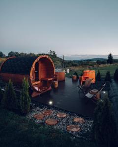 eine kreisförmige Holzhütte mit einer Terrasse und Stühlen im Hof in der Unterkunft Jeleni Jar Apartamenty in Duszniki-Zdrój