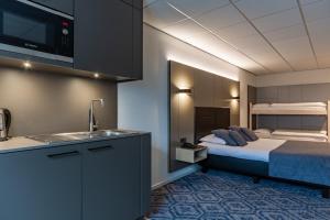uma cozinha com uma cama e um lavatório num quarto em Hotel Edenpark em Brunssum