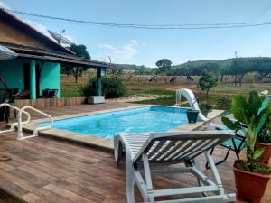 a swimming pool with a chair and a house at Chácara Recanto da Paz in Pirenópolis