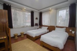 dwa łóżka w pokoju z dwoma oknami w obiekcie Yalamul Garden w mieście Patan