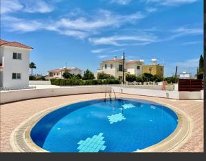 a large blue swimming pool in a yard with houses at Andris apartment in Paralimni
