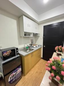 una pequeña cocina con fregadero y nevera negra en Cozy Mesaverte Condo Residences, en Cagayan de Oro
