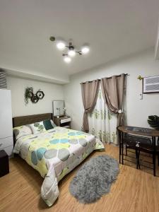 a bedroom with a bed and a table and a window at Cozy Mesaverte Condo Residences in Cagayan de Oro