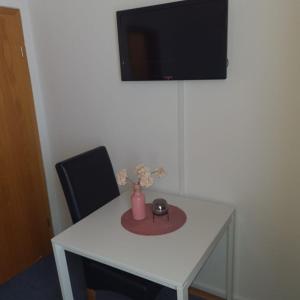 a white table with a black chair and a vase with flowers at Hotel Dalmacija in Mayen